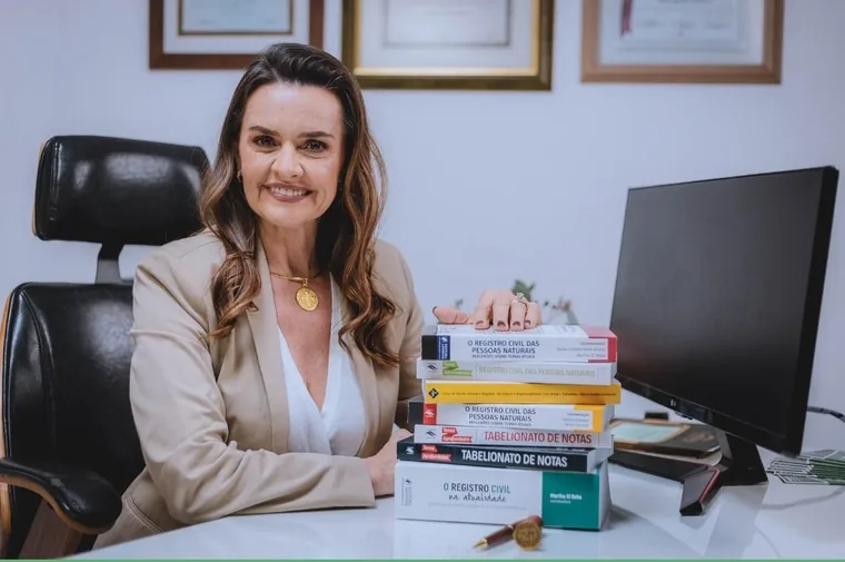 A tabeliã Márcia Rosália Schwarzer em seu gabinete, ao lado dos livros que publicou